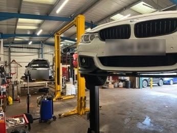 Inside the Blossomgate Motors workshop, a car raised on a yellow two-post lift