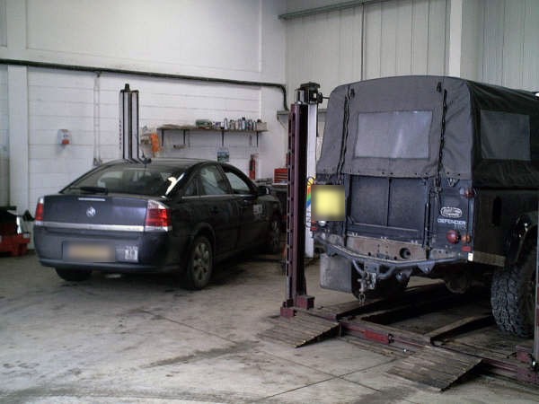 A saloon car and a Land Rover Defender in the MOT bay at Blossomgate Motors