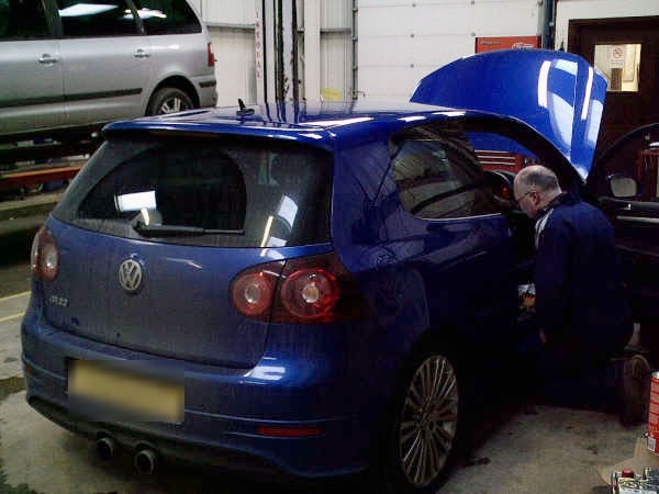A Blossomgate Motors mechanic working under the bonnet of a blue hatchback in the workshop